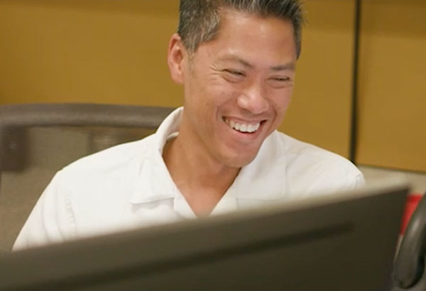 Laughing employee behind computer monitor